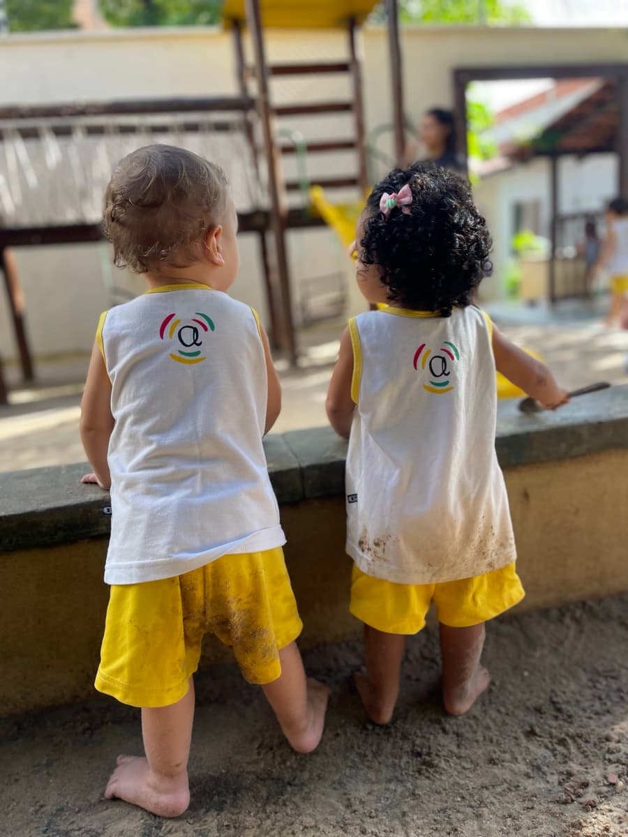 Dois bebês de uniforme observando o quintal
