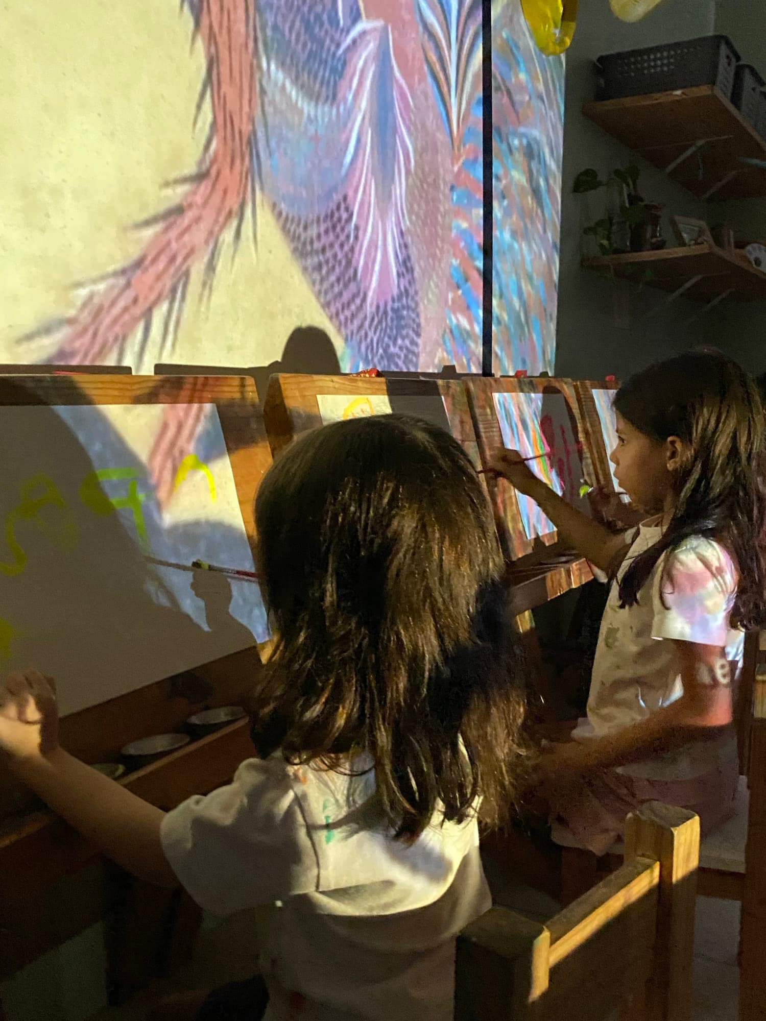 Crianças pintando em cavaletes com projeção de pássaros
