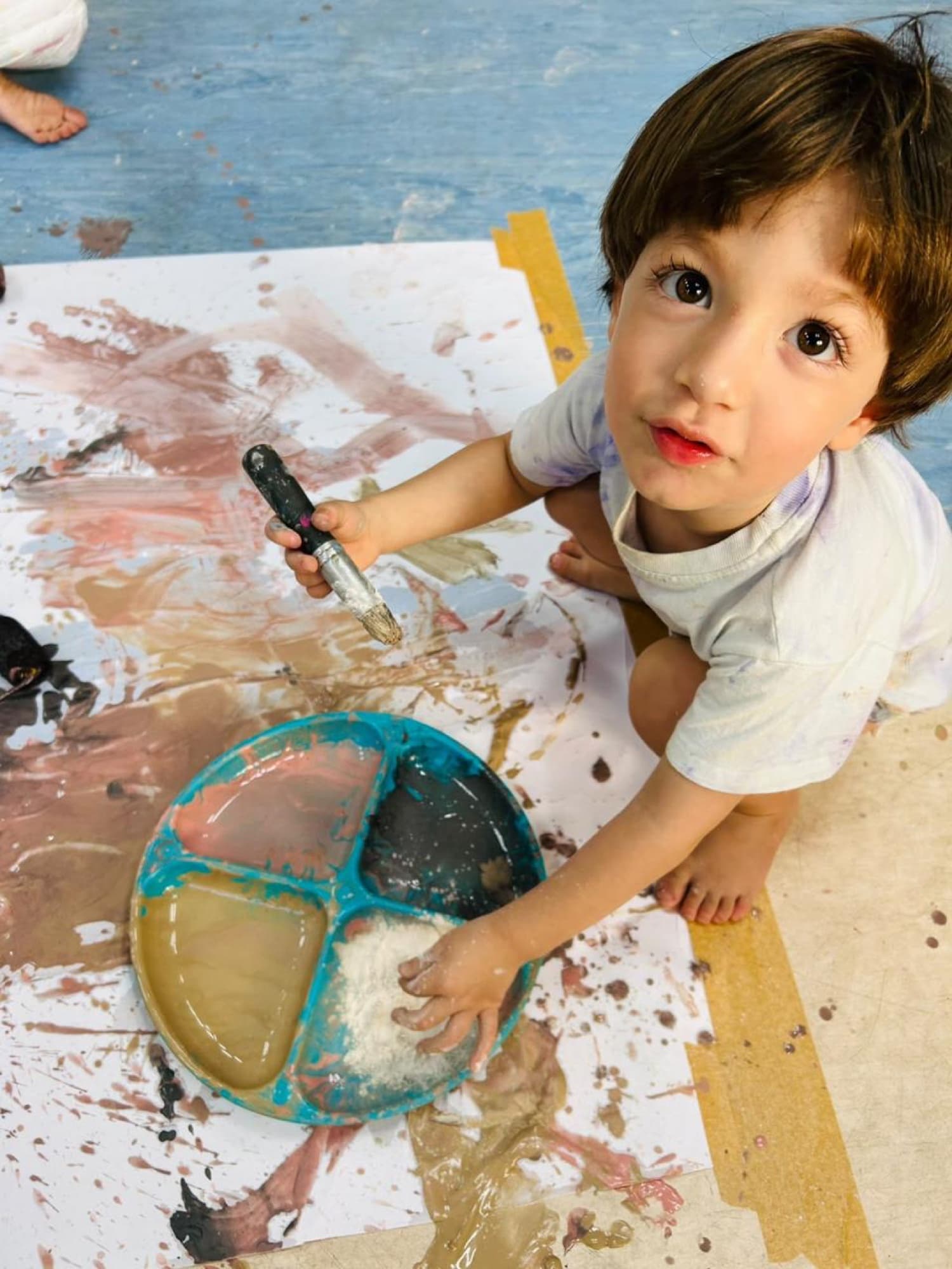 Menino com pincel e paleta de tintas no Ateliê Aquarela